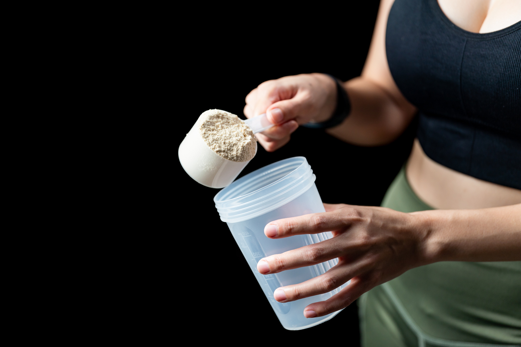 Woman Measuring Scoop of Whey Protein and Shake